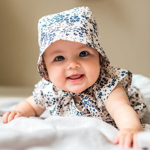 baby wearing Petits Genoux Floral Cotton Bonnet the perfect baby shower gift
